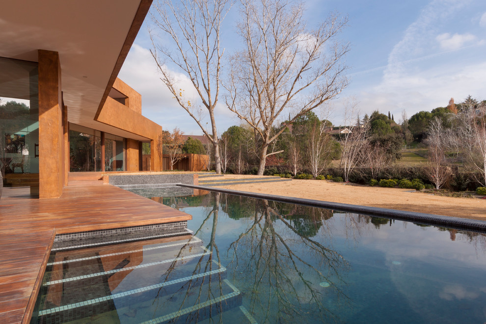 Idée de décoration pour une piscine design de taille moyenne et rectangle avec une terrasse en bois.