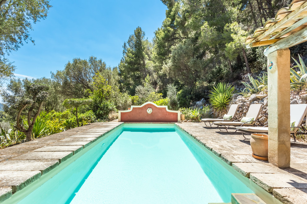Aménagement d'une piscine arrière méditerranéenne de taille moyenne et rectangle avec des pavés en pierre naturelle.