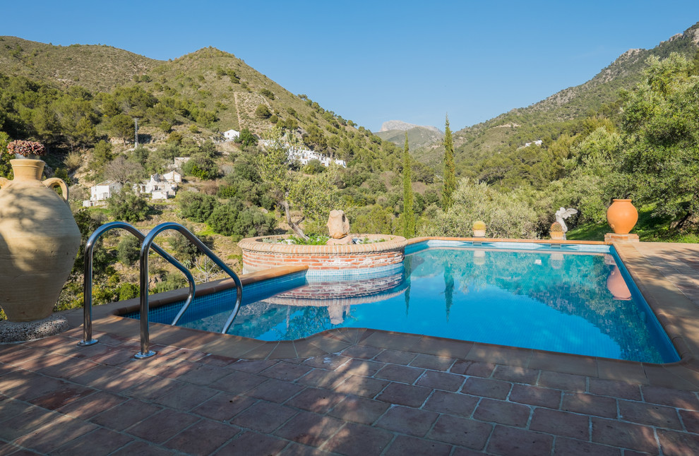 Modelo de piscina alargada mediterránea grande a medida en patio trasero con adoquines de ladrillo