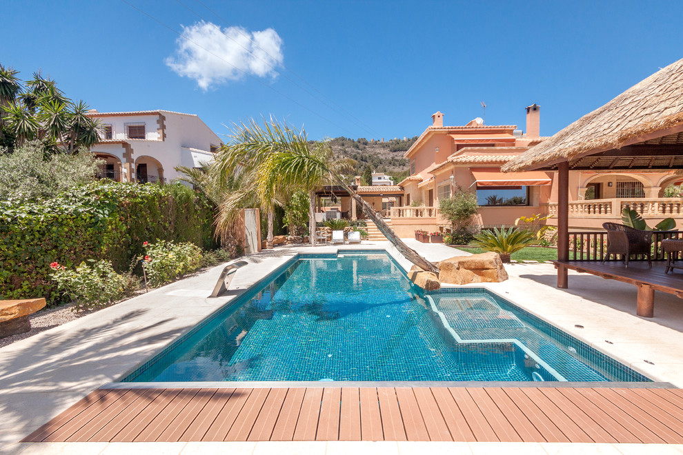 Modelo de casa de la piscina y piscina alargada mediterránea grande rectangular en patio trasero con entablado