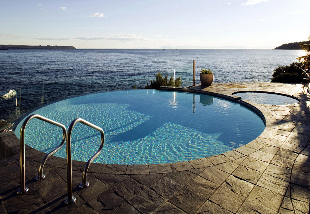 Foto de piscina infinita clásica renovada de tamaño medio redondeada en patio con suelo de baldosas