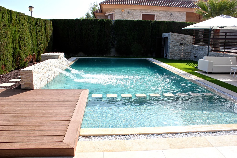 Medium sized modern back custom shaped swimming pool in Other with a water feature.