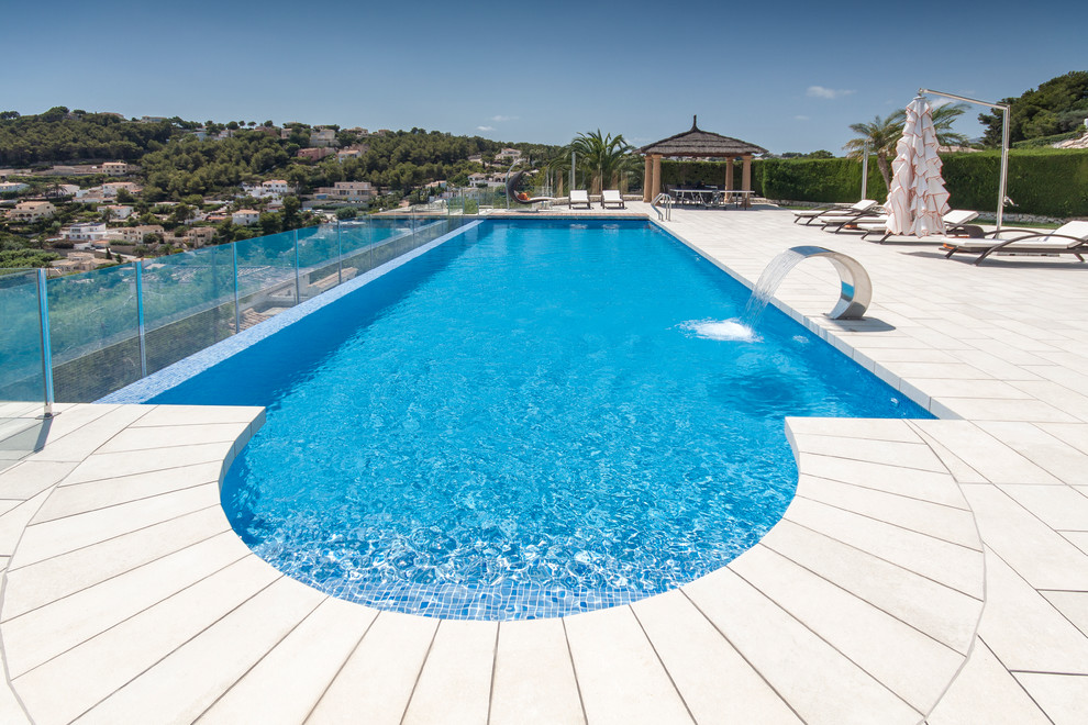 Idée de décoration pour une grande piscine méditerranéenne rectangle avec un point d'eau.