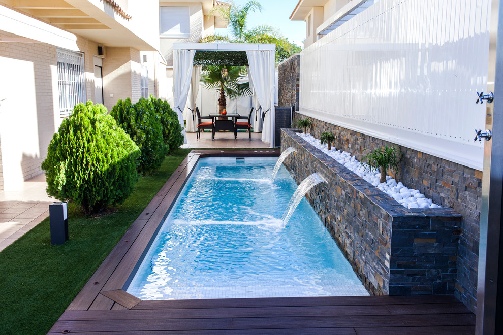 Foto de piscina alargada contemporánea de tamaño medio rectangular en patio lateral con entablado