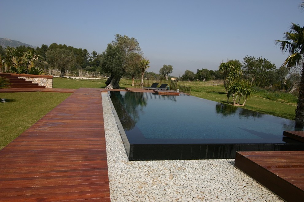 Foto de piscina alargada moderna grande a medida en patio trasero con adoquines de piedra natural