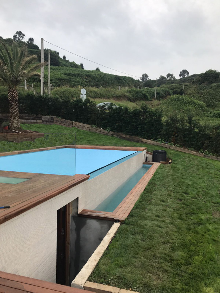 Imagen de casa de la piscina y piscina infinita costera de tamaño medio rectangular en patio lateral con entablado