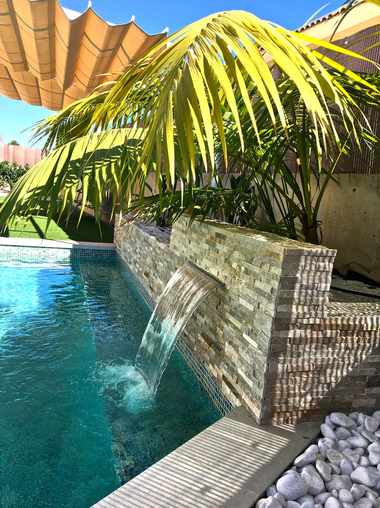 Esempio di una piscina tropicale con fontane