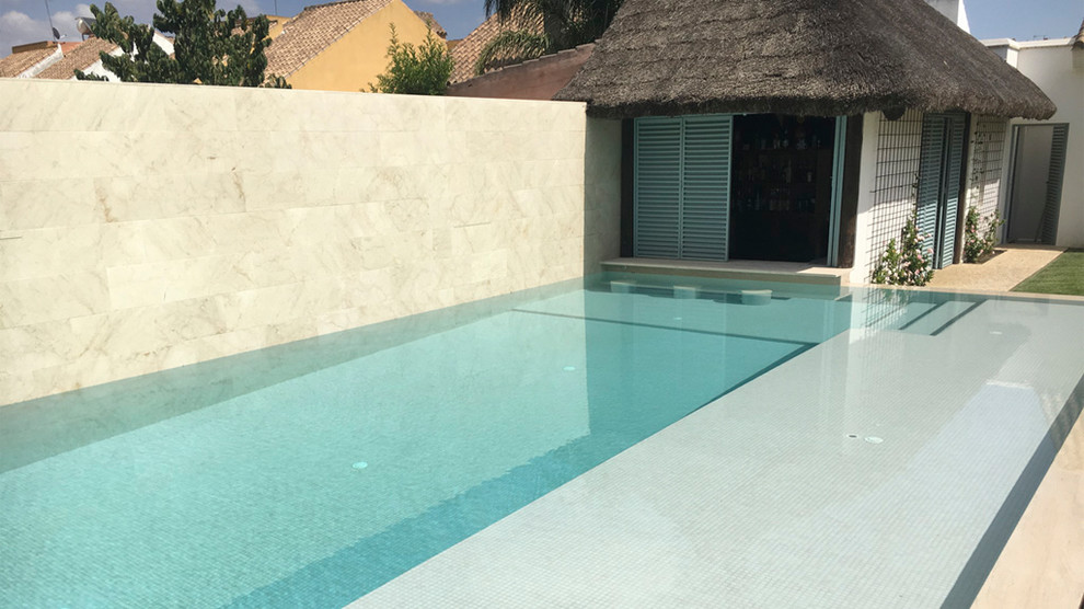 Immagine di una grande piscina monocorsia tropicale rettangolare dietro casa con una dépendance a bordo piscina