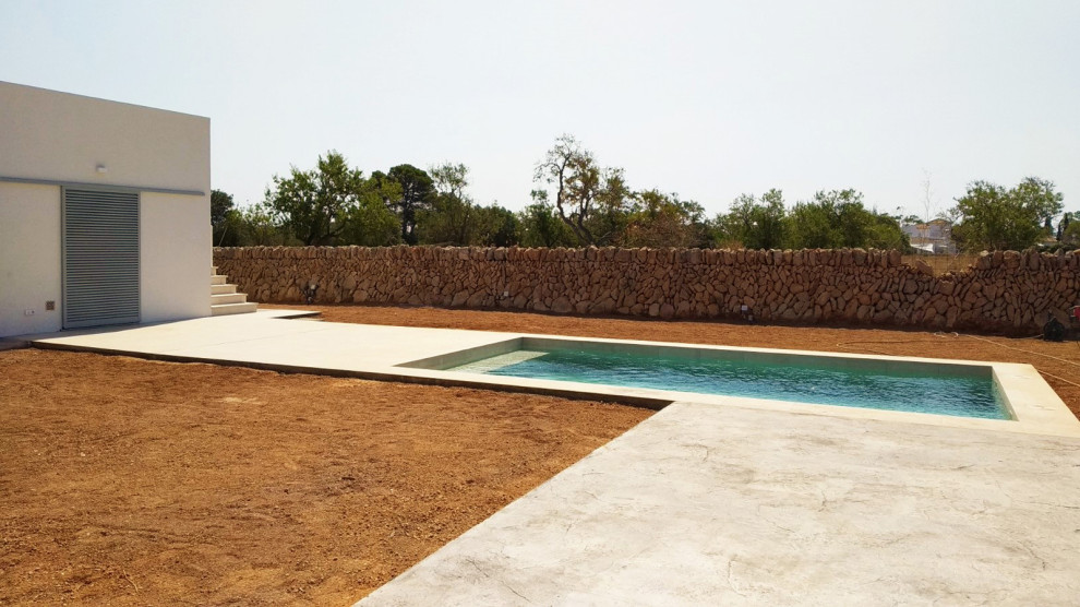 На фото: прямоугольный бассейн на внутреннем дворе в средиземноморском стиле с перегородкой для приватности и покрытием из декоративного бетона с