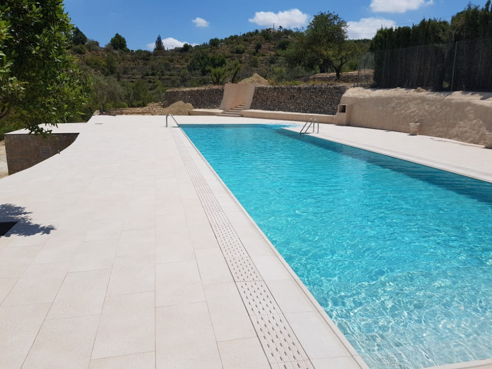 Photo of a large mediterranean back rectangular lengths swimming pool in Madrid with with pool landscaping and tiled flooring.