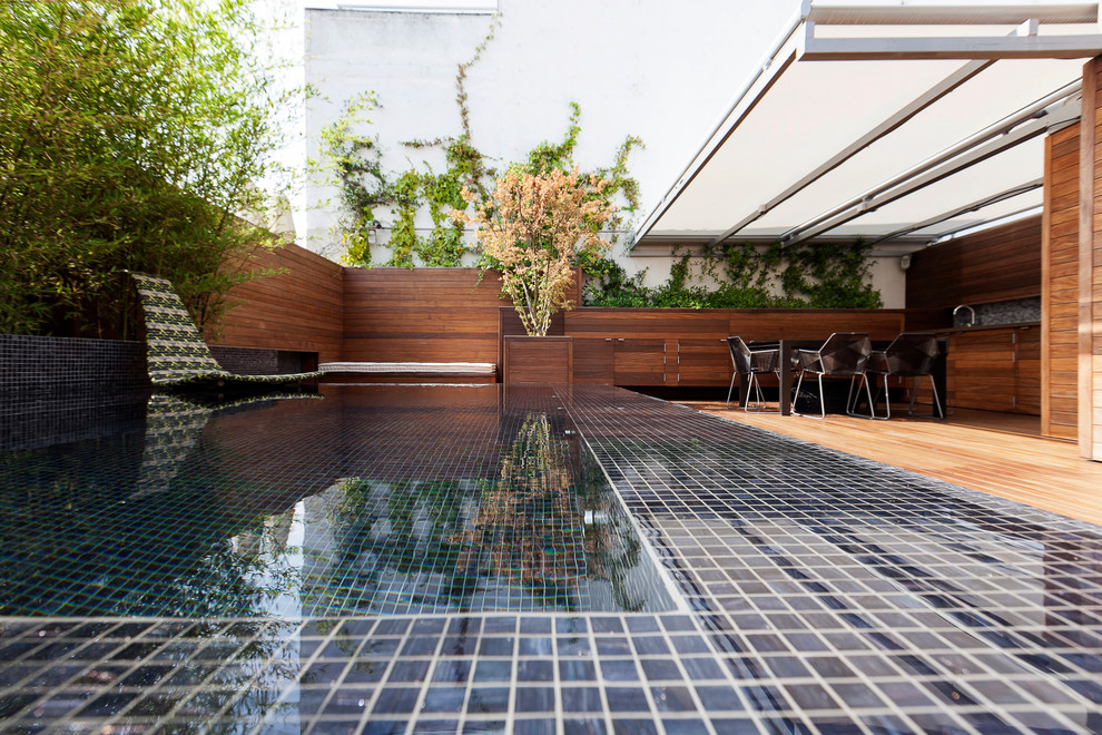 Ejemplo de piscina actual rectangular en patio trasero con suelo de baldosas