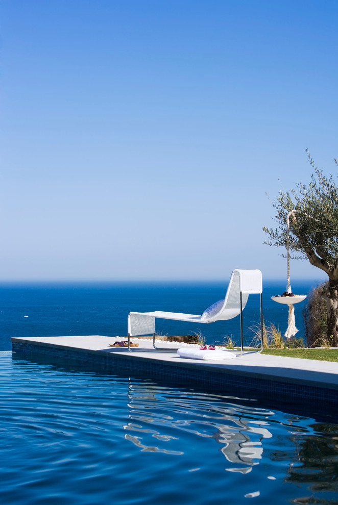 Aménagement d'une grande piscine à débordement et arrière méditerranéenne rectangle.