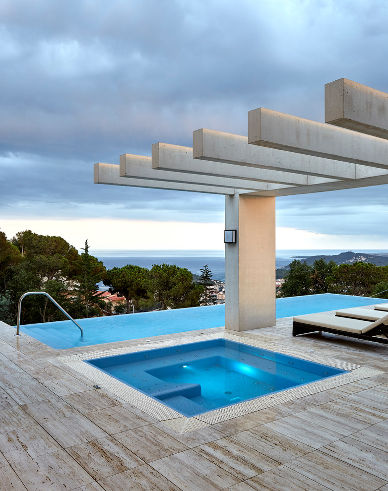 Idée de décoration pour une grande piscine à débordement design rectangle avec un bain bouillonnant.