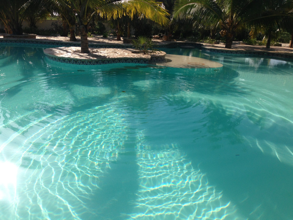 На фото: огромный наземный бассейн в форме фасоли на внутреннем дворе в средиземноморском стиле с домиком у бассейна и покрытием из каменной брусчатки
