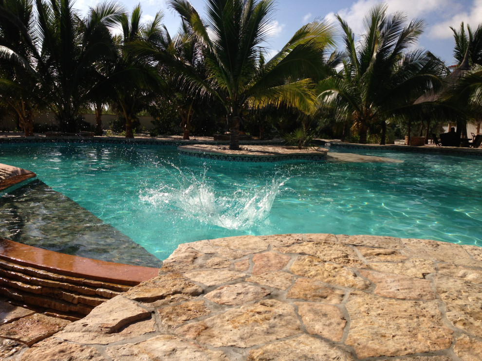 Imagen de casa de la piscina y piscina elevada mediterránea extra grande tipo riñón en patio con adoquines de piedra natural