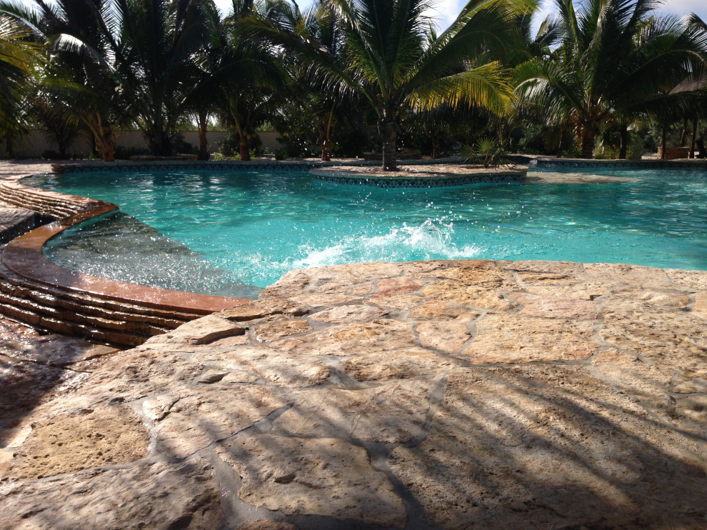 Bild på en mycket stor medelhavsstil njurformad pool, med poolhus och naturstensplattor
