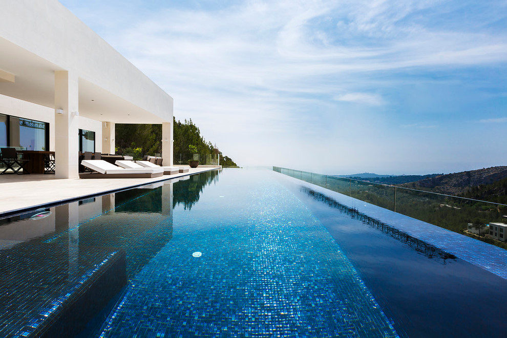 Immagine di una piscina a sfioro infinito design rettangolare di medie dimensioni e davanti casa con una dépendance a bordo piscina
