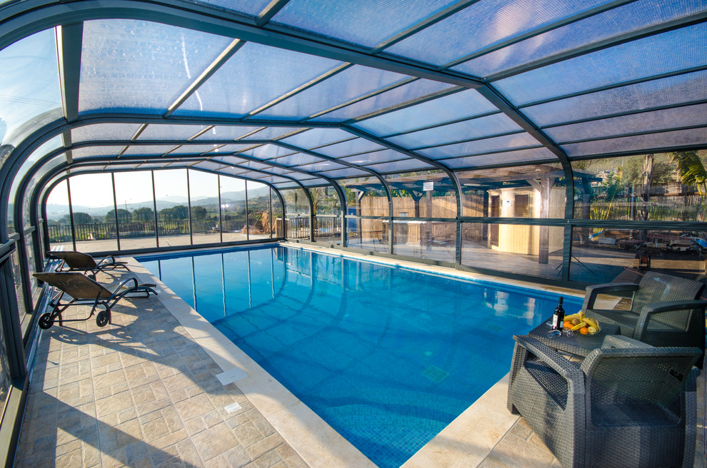 Imagen de casa de la piscina y piscina alargada actual de tamaño medio rectangular en patio con adoquines de piedra natural