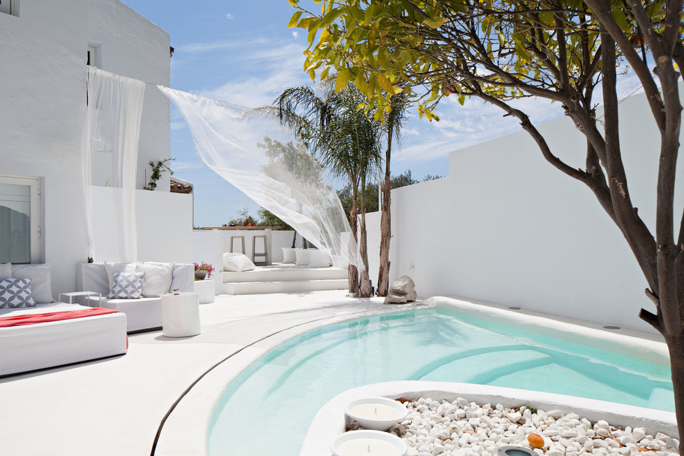 Immagine di una piscina mediterranea personalizzata dietro casa e di medie dimensioni con lastre di cemento e una dépendance a bordo piscina