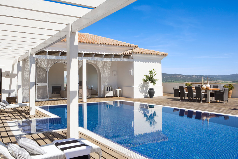 Modelo de casa de la piscina y piscina alargada mediterránea de tamaño medio rectangular en patio delantero con entablado