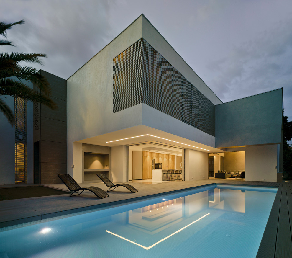 Пример оригинального дизайна: большой прямоугольный бассейн на заднем дворе в стиле модернизм с настилом