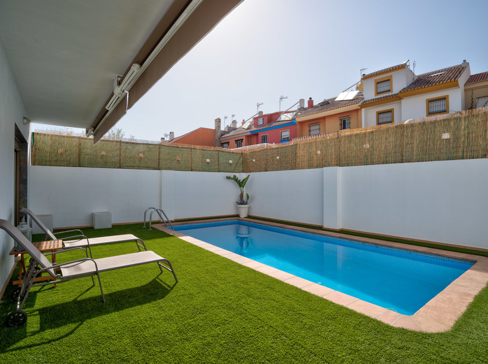 Modelo de piscina alargada mediterránea rectangular en patio trasero con suelo de baldosas