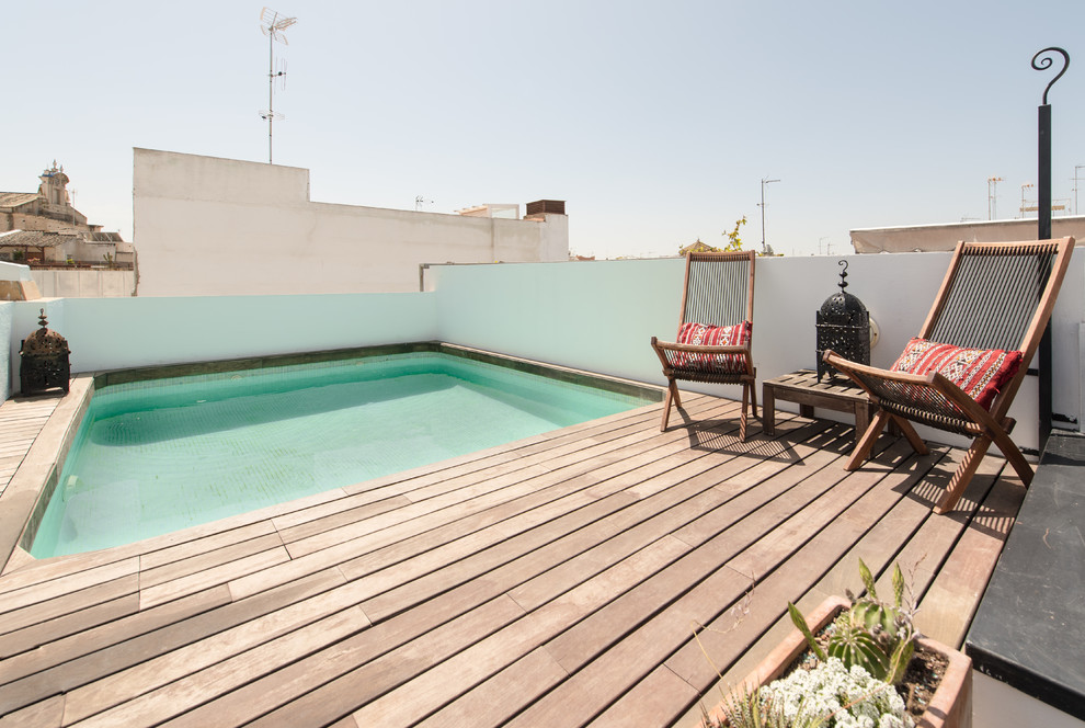 Cette image montre une petite piscine sur toit méditerranéenne rectangle avec une terrasse en bois.
