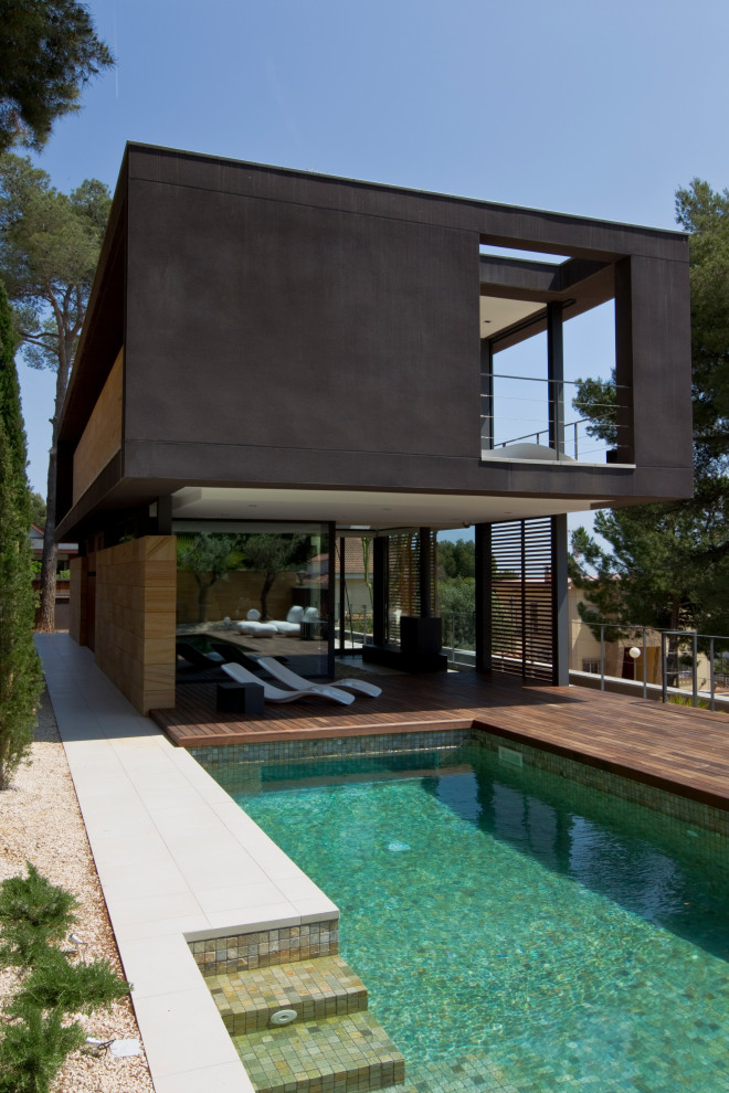 Ispirazione per una piscina design rettangolare di medie dimensioni e dietro casa con piastrelle