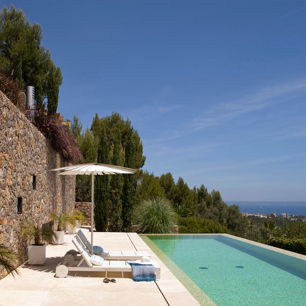 Foto de casa de la piscina y piscina infinita mediterránea de tamaño medio rectangular con adoquines de piedra natural