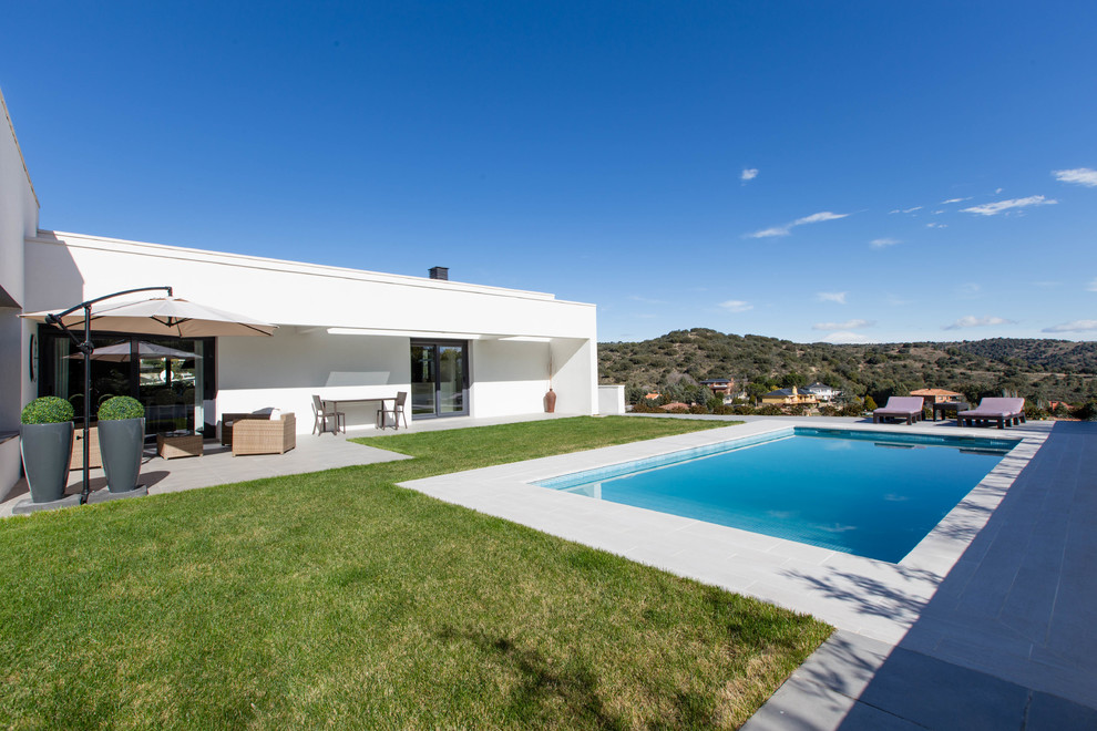 Ejemplo de casa de la piscina y piscina alargada actual de tamaño medio rectangular en patio delantero