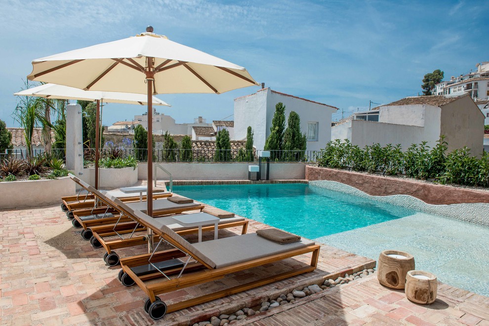 Diseño de piscina alargada mediterránea pequeña a medida en patio con adoquines de ladrillo