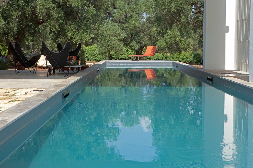 Bild på en mellanstor lantlig rektangulär pool på baksidan av huset, med naturstensplattor