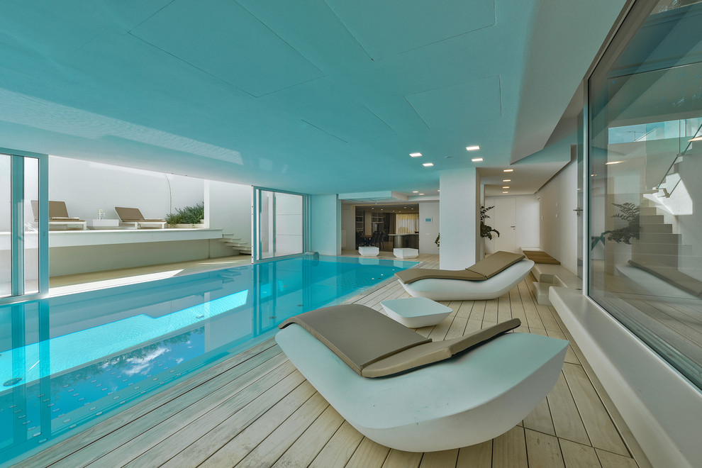 Inspiration pour une piscine intérieure minimaliste rectangle avec une terrasse en bois.