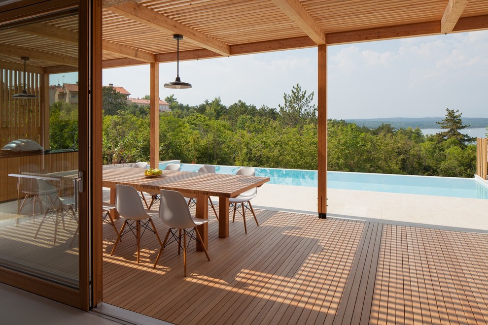 Diseño de piscina infinita escandinava grande rectangular en patio con adoquines de hormigón