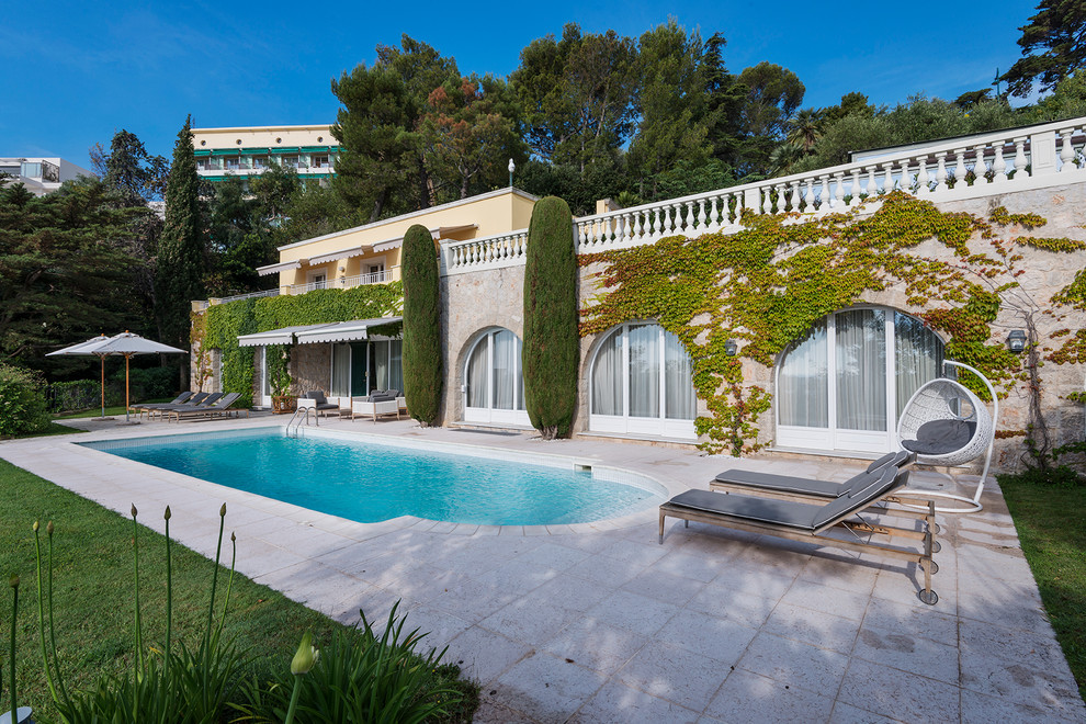 Esempio di un'ampia piscina mediterranea personalizzata dietro casa con pavimentazioni in pietra naturale