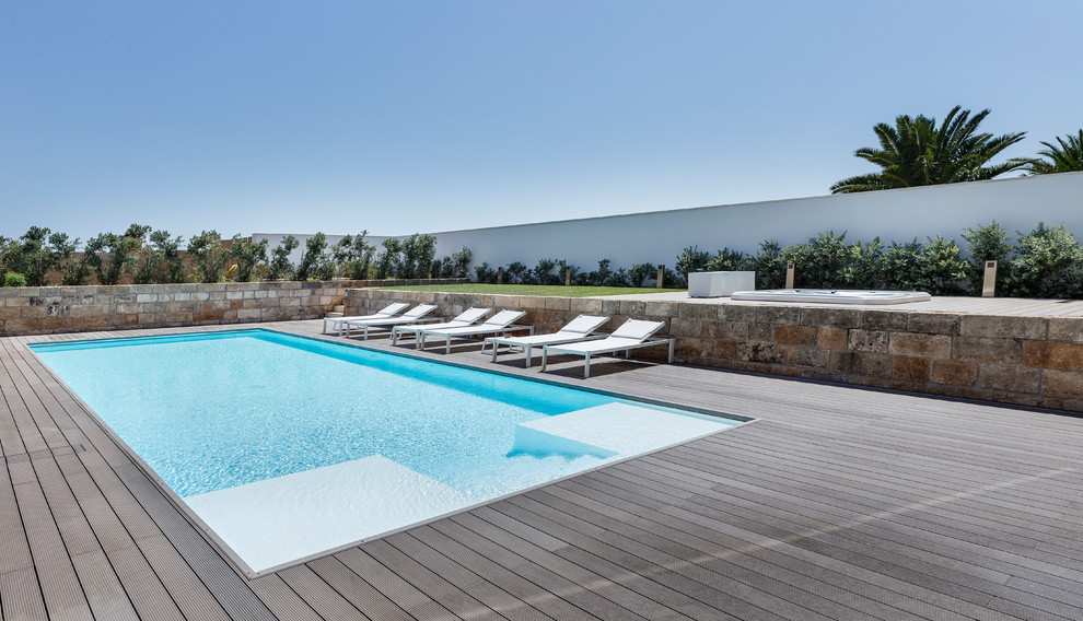Foto di una piscina a sfioro infinito minimalista rettangolare di medie dimensioni e dietro casa con pedane