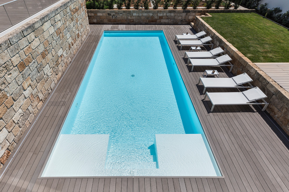 Inspiration pour une piscine à débordement et arrière minimaliste de taille moyenne et sur mesure avec une terrasse en bois.