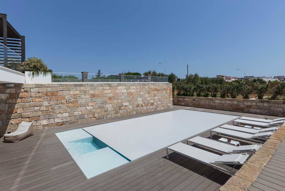Inspiration pour une piscine à débordement et arrière minimaliste de taille moyenne et rectangle avec une terrasse en bois.
