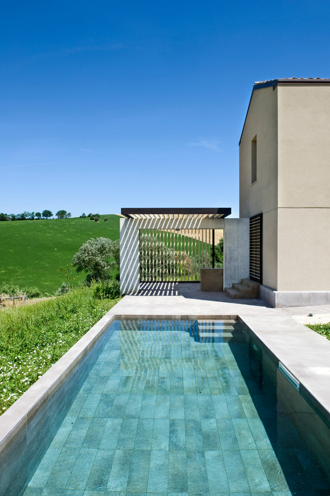 Exempel på en mellanstor modern rektangulär pool längs med huset, med marksten i betong