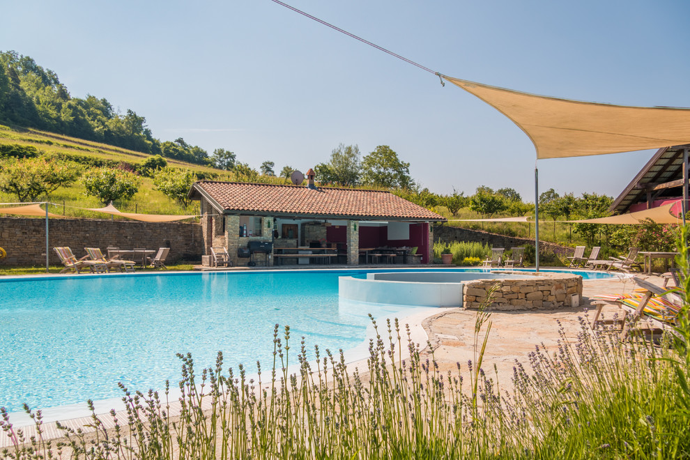 Esempio di una grande piscina a sfioro infinito country personalizzata davanti casa con una vasca idromassaggio e pavimentazioni in pietra naturale