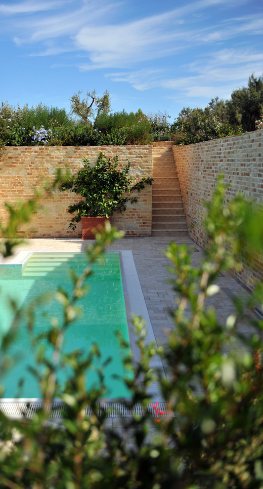 Immagine di una grande piscina mediterranea rettangolare davanti casa con una dépendance a bordo piscina e pavimentazioni in pietra naturale