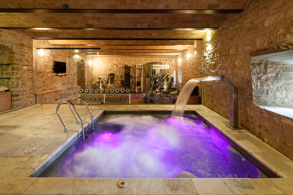 Cette image montre une petite piscine intérieure design rectangle avec un point d'eau et des pavés en pierre naturelle.