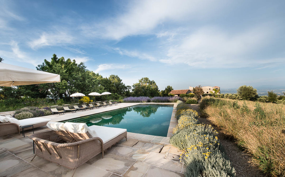 Foto di un'ampia piscina country rettangolare dietro casa con pavimentazioni in pietra naturale