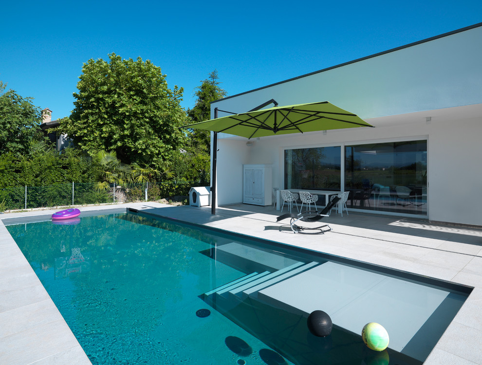 Modelo de piscina infinita contemporánea de tamaño medio rectangular en patio trasero con adoquines de piedra natural