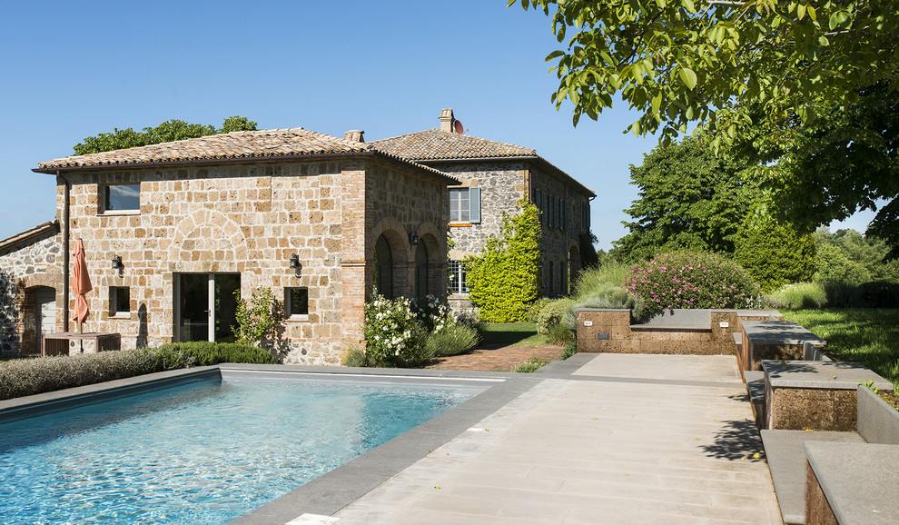 Diseño de casa de la piscina y piscina de estilo de casa de campo de tamaño medio rectangular en patio lateral con adoquines de piedra natural