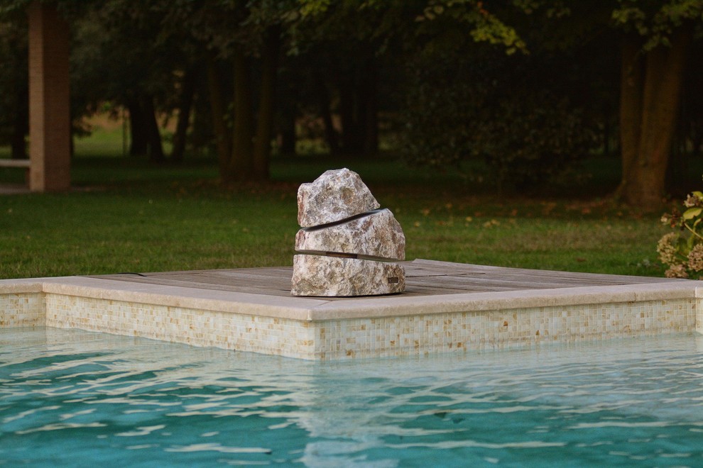 Exempel på en lantlig anpassad pool framför huset, med poolhus och naturstensplattor