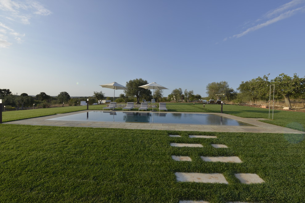 Ispirazione per una piscina a sfioro infinito country rettangolare di medie dimensioni e dietro casa con pavimentazioni in pietra naturale
