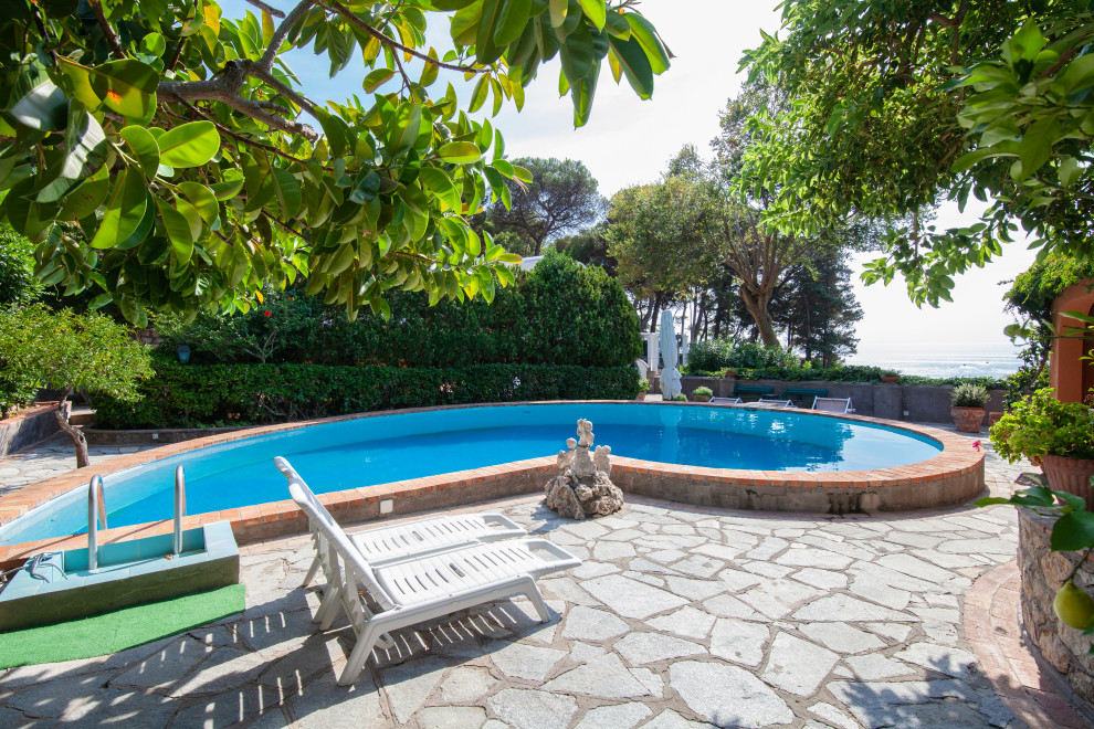 Esempio di una piscina mediterranea personalizzata con pavimentazioni in pietra naturale