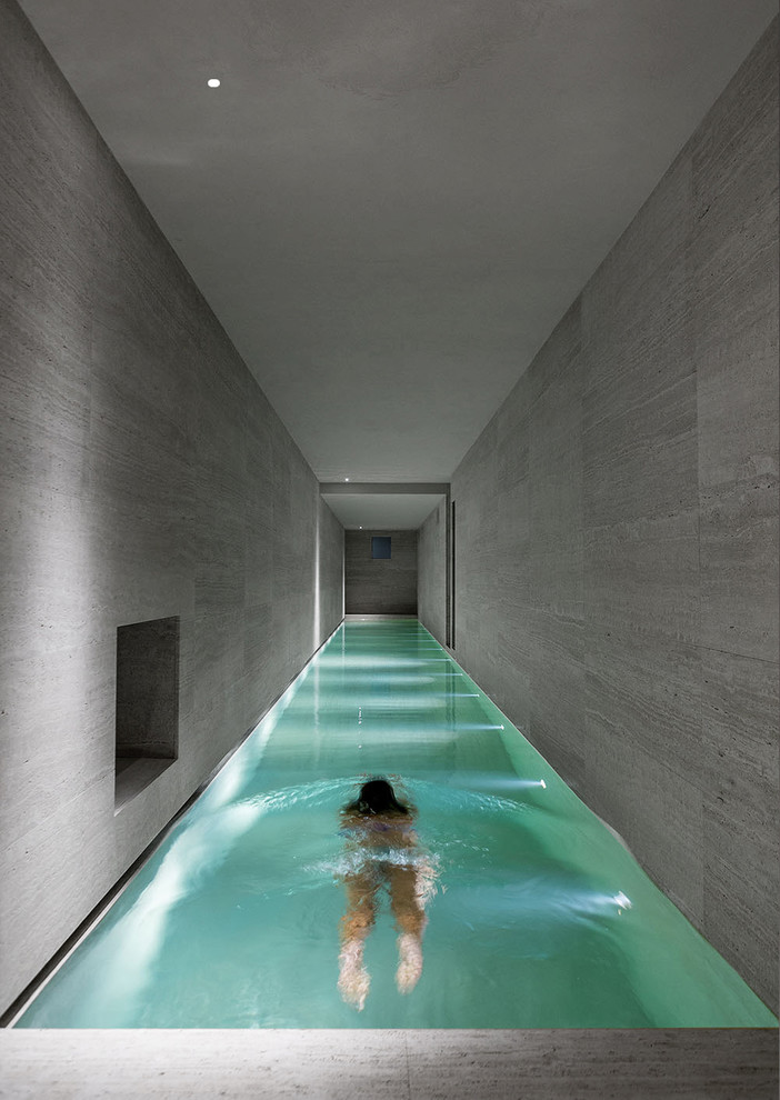 Cette photo montre une piscine intérieure moderne de taille moyenne et rectangle avec des pavés en pierre naturelle.