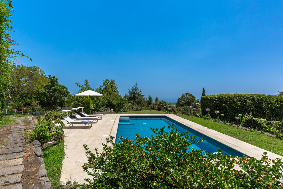 Immagine di una grande piscina country rettangolare con pavimentazioni in pietra naturale